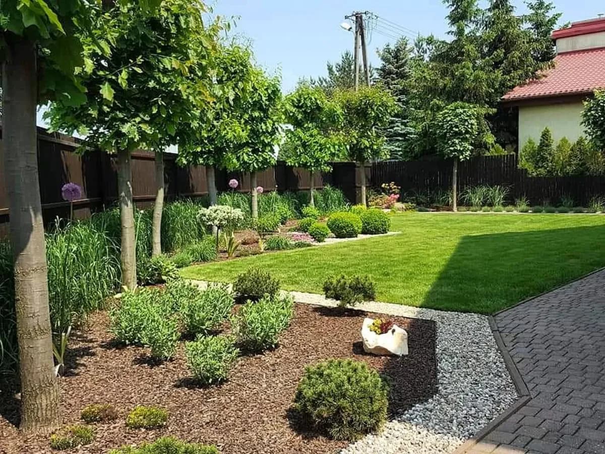 Ogród z trawnikiem, rabatą i ścieżką z kostki